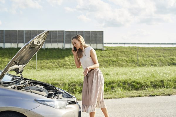 Caucasian woman with broken car calling for help at the road