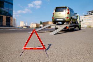 Red warning foldable triangle placed before tow track. Caution road sign and towing service. Closeup
